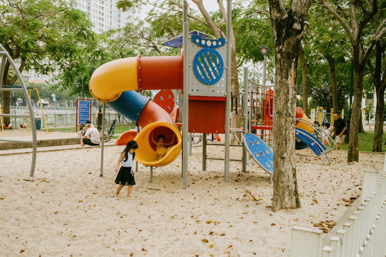 Kids enjoying colorful slides and play structures in an outdoor park playground.